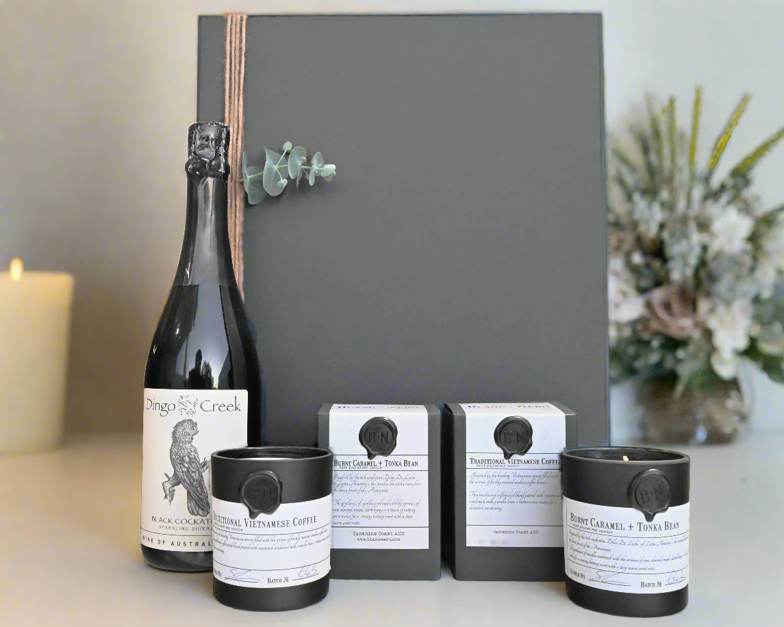 Wine bottle, coffee packaging, and candles in front of hamper box