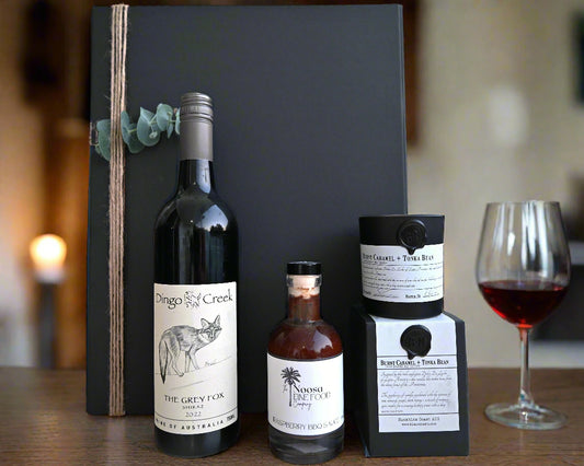 Bottle of Dingo Creek wine and two other bottles on a surface with a plant in the background