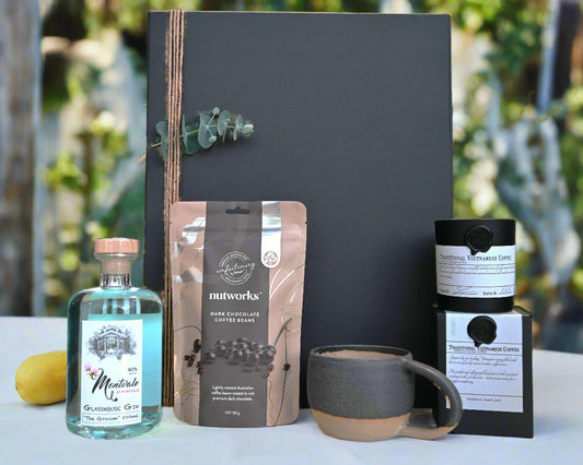 Collection of items including a bottle, coffee mug, in front of a hamper box
