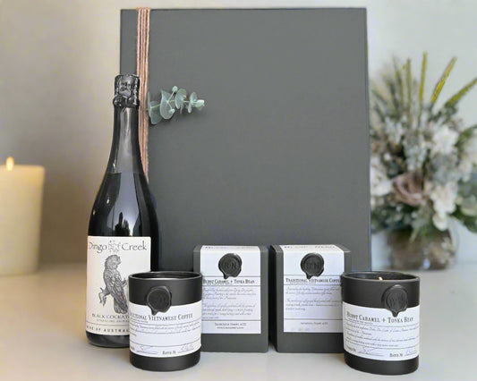 Wine bottle, coffee packaging, and candles in front of hamper box