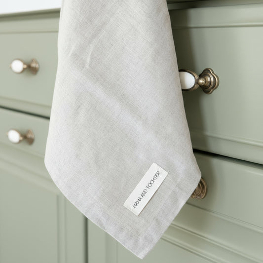 Gray kitchen towel hanging on a faucet with a Mama and Tochter label in a kitchen setting