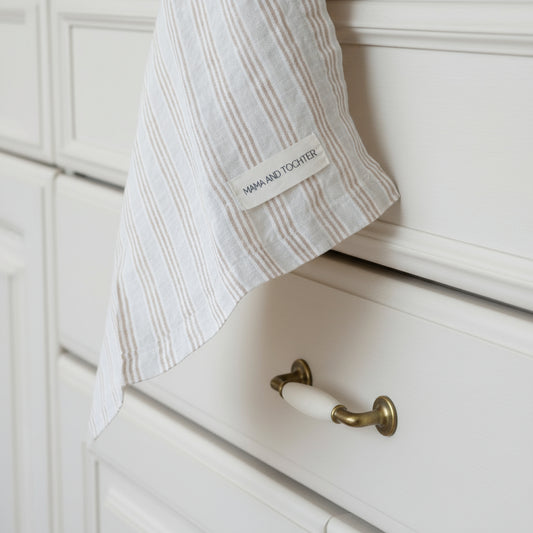 Striped towel with a brand label hanging against a neutral background