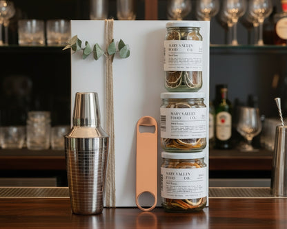 Cocktail hamper with cocktail shaker, bottle opener and dried lemon, lime and orange.