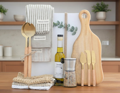 Wooden kitchen utensils including a cutting board, spoons, and a salt grinder on a table with a neutral background.