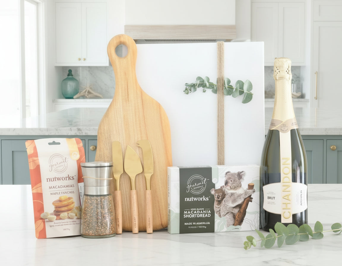 Bottle of champagne, wooden cutting board, and other items on a table with a neutral background